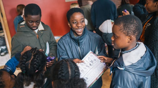 A group of children smiling and looking at something in a book